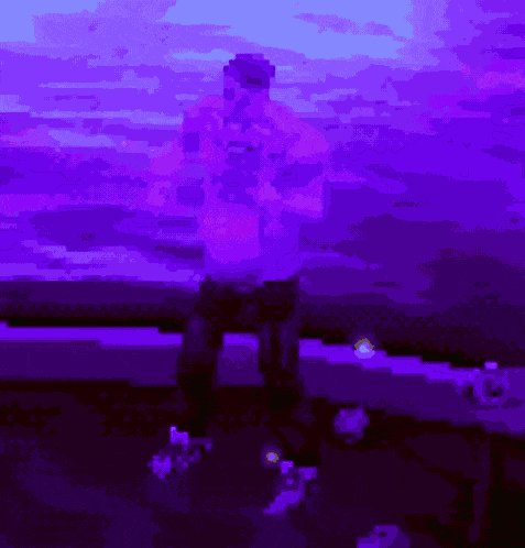 a man in a purple shirt is standing in front of a purple sky
