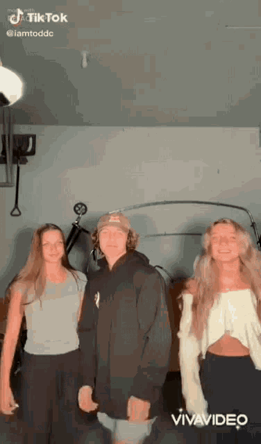 a group of three people are standing next to each other in a garage .