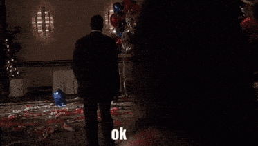 a man in a suit and tie says ok in front of a woman in a pink suit