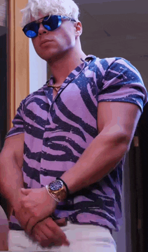 a man wearing a zebra print shirt and sunglasses is standing with his hands on his hips