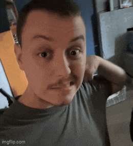 a man with a mustache is making a funny face while wearing a grey shirt .