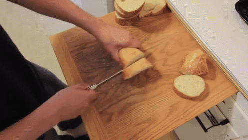 a person is cutting bread on a cutting board with a knife