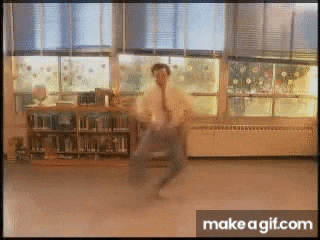 a man in a white shirt and tie is dancing in front of a window in a library .