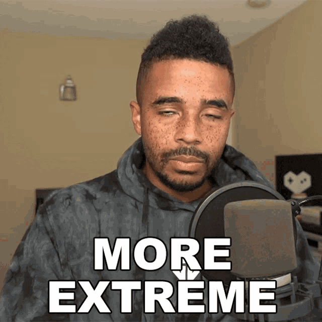 a man stands in front of a microphone with the words more extreme written above him