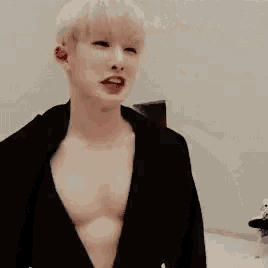 a young man is standing in a room without a shirt on and looking at the camera .