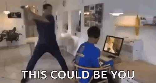 a man is dancing in front of a computer while a boy sits in front of a computer .
