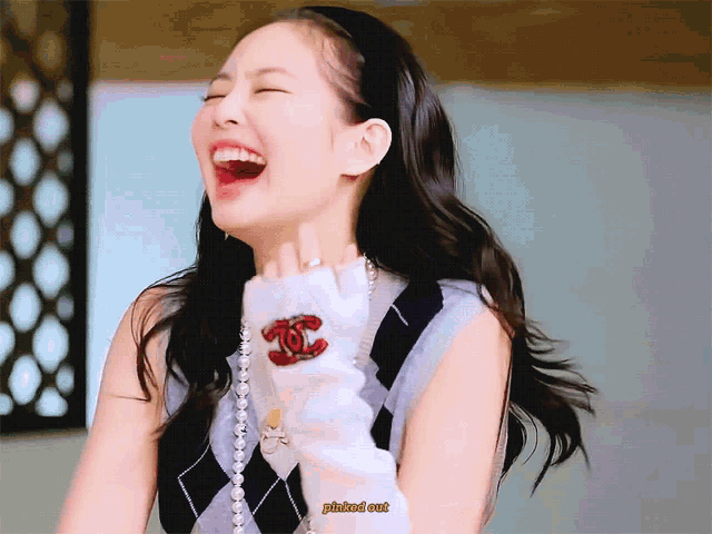 a woman wearing a chanel sweater laughs with her mouth open