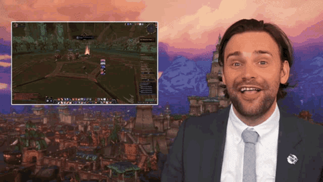 a man in a suit and tie is smiling in front of a screen with a game on it