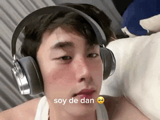 a young man wearing headphones is laying on a bed and has a smiley face on his face .