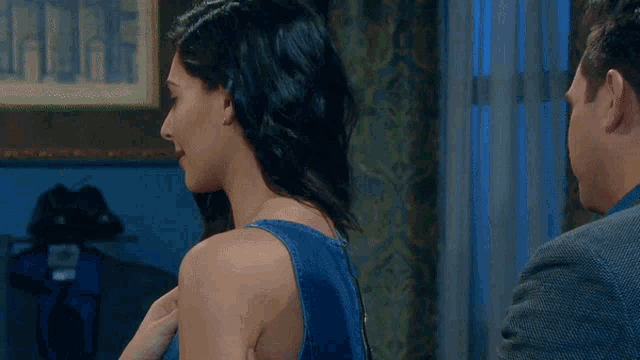 a woman in a blue top is looking at a man in a suit