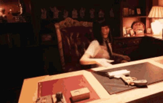a woman is sitting at a table with a gun on it
