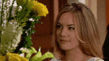 a woman stands in front of a bouquet of yellow and white flowers and the word phantom is on the bottom right