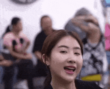 a close up of a woman 's face with her mouth open and people sitting in the background .