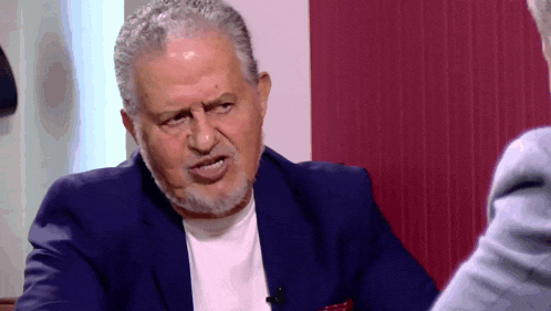 a man with gray hair and a beard is talking to another man