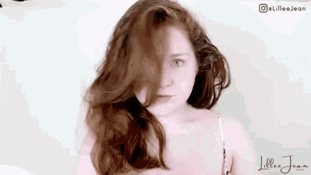 a young girl with red hair is standing in front of a white wall .