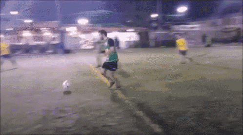 a man in a green shirt kicking a soccer ball on a field