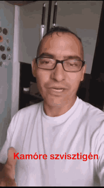 a man wearing glasses and a white shirt with the words kamore szvisztigen on the bottom