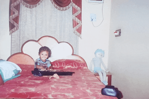 a little boy sitting on a bed with a keyboard