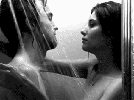 a man and a woman are taking a shower together and kissing .