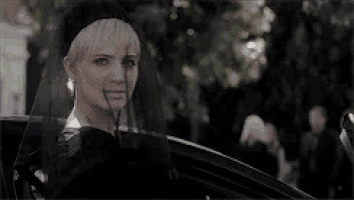 a woman wearing a black veil and a black hat is sitting in a car .