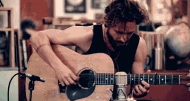 a man is playing a guitar in front of a microphone .