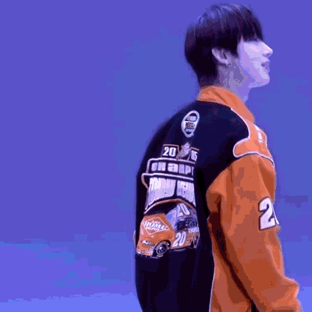 a man wearing an orange and black varsity jacket with the number 2 on the back