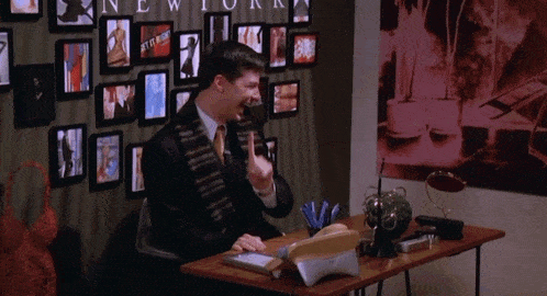 a man sits at a desk in front of a wall that has a picture on it that says " lingerie "
