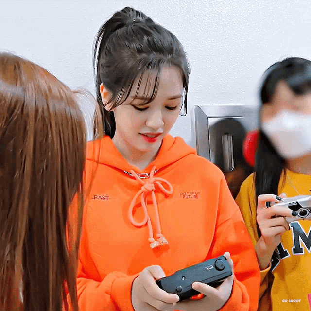 a girl wearing an orange hoodie that says " present " on it