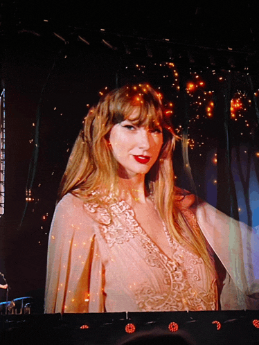 a woman with red lipstick is on a stage in front of a large screen