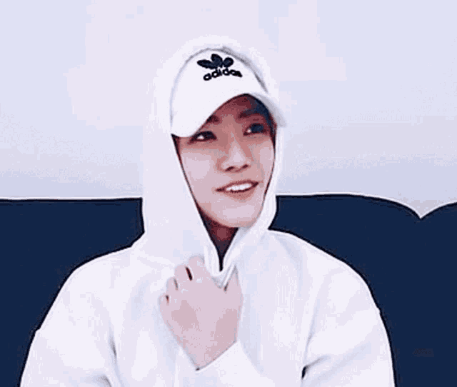 a young man is wearing a white hoodie and a white hat .