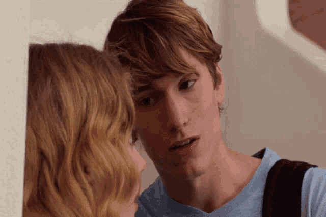 a man and a woman are looking at each other and the man is wearing a blue shirt