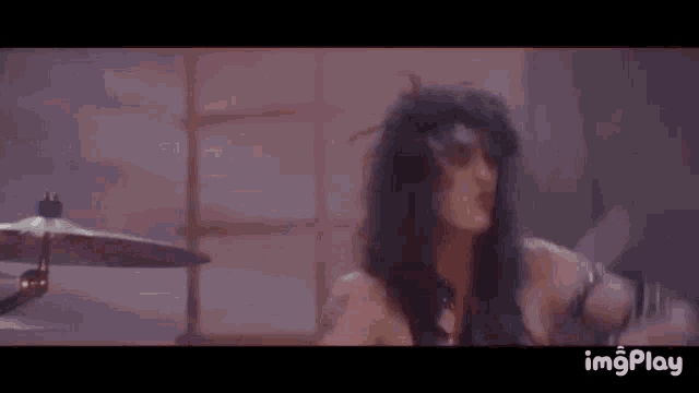 a woman is playing a drum set in a dark room while wearing boxing gloves .