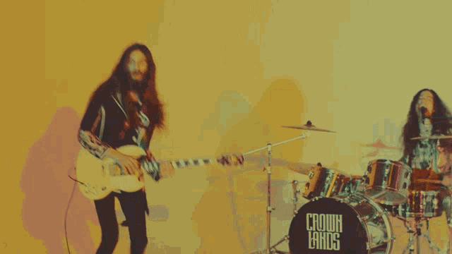 a blurred image of a man playing a guitar and a drummer wearing a shirt that says cannibal kings