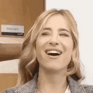 a close up of a woman laughing with her eyes closed and her mouth open .