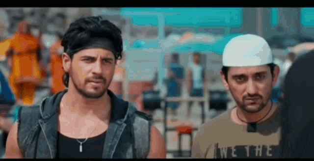 two men are standing next to each other and looking at each other in a movie .
