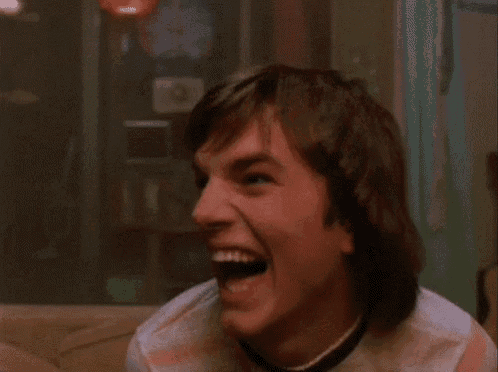 a man is laughing while sitting on a couch in a room
