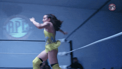 a woman in a yellow dress is in a wrestling ring with a logo that says opb