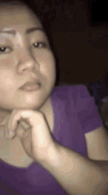 a close up of a woman 's face with her hand on her chin .