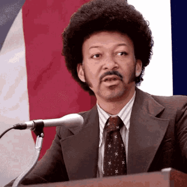 a man in a suit and tie stands at a podium giving a speech