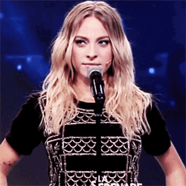 a woman stands in front of a microphone with the word fool on the bottom right