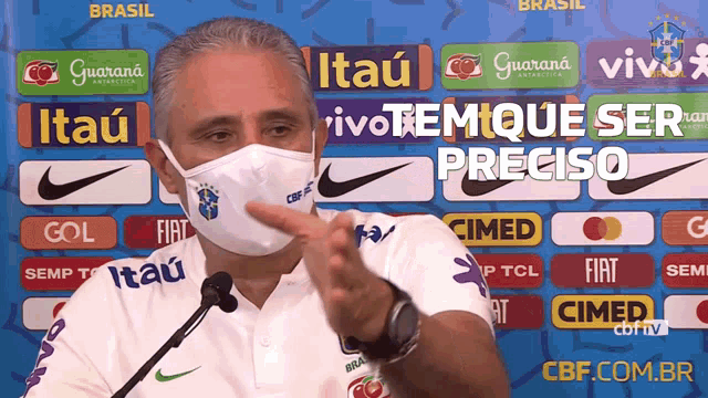 a man wearing a face mask is giving a speech in front of advertisements for itau guarana and vivo