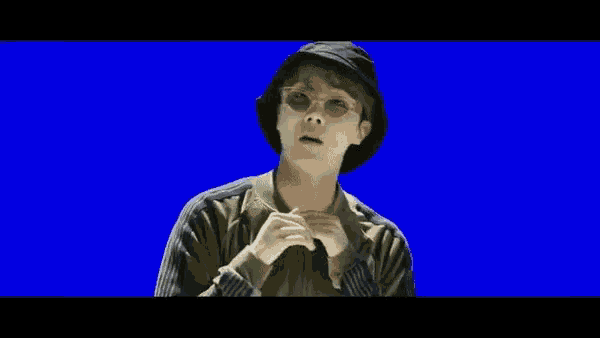 a man wearing a hat and glasses is standing on a blue background