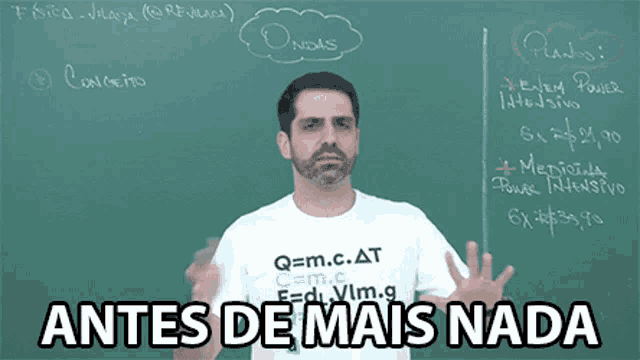 a man wearing a shirt that says q = m.c.at stands in front of a chalkboard