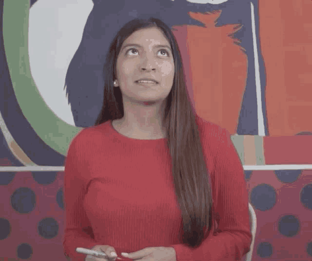 a woman in a red sweater is smiling and holding a cell phone