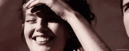 a woman is laughing with her hand on her face .