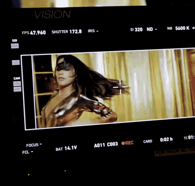 a woman in a gold dress is being recorded on a vision camera