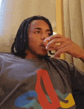 a man with dreadlocks is wearing a shirt that says playstation