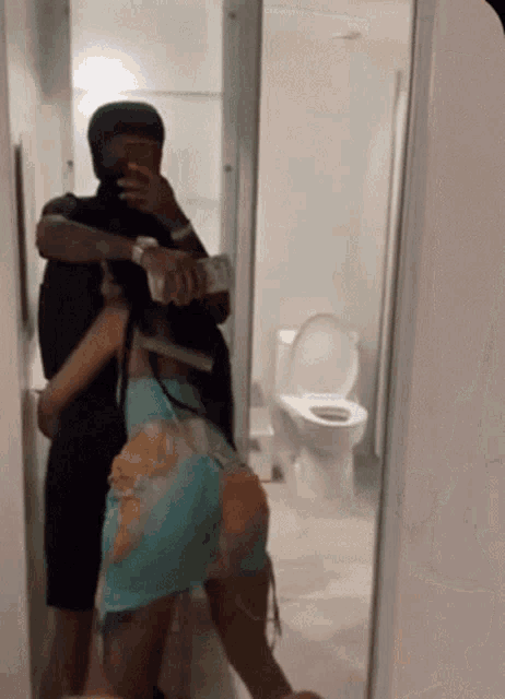 a man is taking a picture of a woman in a bathroom mirror