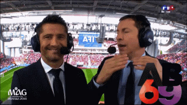 two men wearing headphones are talking in front of a stadium that says art