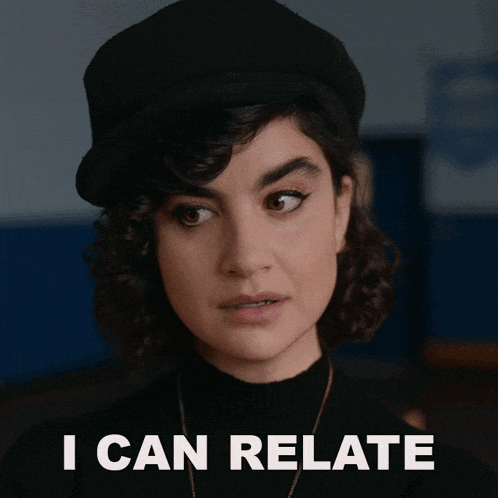 a woman with curly hair wearing a black hat and sweater says i can relate